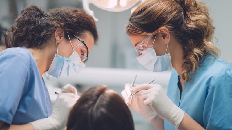 Two dentists treating a patient